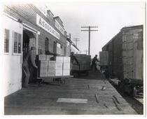 Loading boxes of Sylmar Brand olive oil onto freight cars at the Olive Grower's Association, Los Angeles, California 