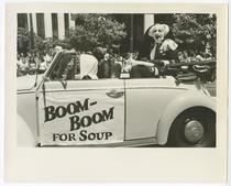 Sister Boom Boom in a convertible with sign that reads: 