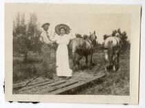 Man and woman riding a hay sled pulled by horses 