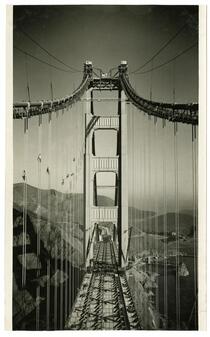 Golden Gate Bridge construction workers painting suspender ropes above completed roadway