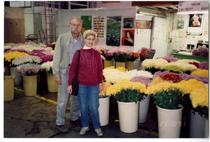 Two people posing in front of flowers at the California Flower Market