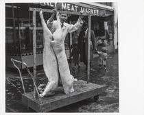 Butcher and butchered pigs in front of meat market, Fillmore Street, San Francisco